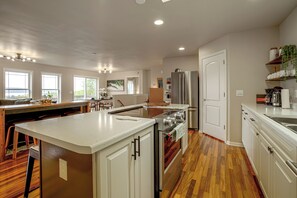 Een moderne keuken met een centraal eiland, roestvrijstalen apparatuur en uitzicht op de omgeving.