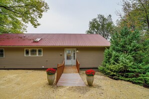 A two-story building with a red roof, a front porch, and a driveway leading to the entrance. - River Views & Gas Fire Table: Maiden Rock Retreat (Maiden Rock)