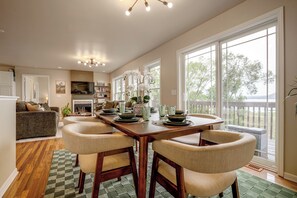 A dining area with a wooden table set for four, surrounded by upholstered chairs. - River Views & Gas Fire Table: Maiden Rock Retreat (Maiden Rock)