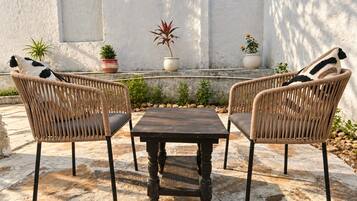 Un patio con due poltrone in vimini, un tavolo in legno e piante in vaso.