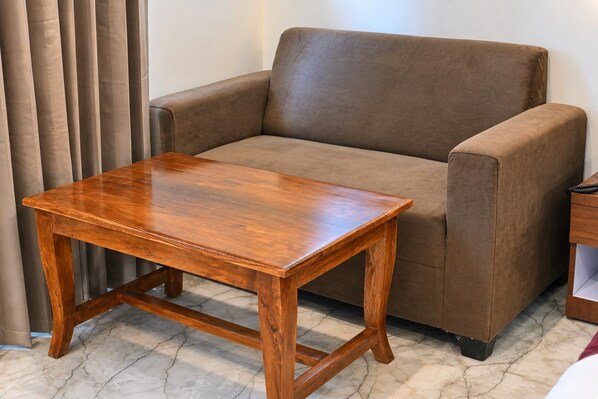 A brown armchair and a wooden table in a room with a marble floor.