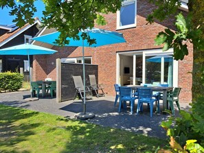 A patio with outdoor seating, a brick building, and a tree. - Holiday Home With 3 Bedrooms (Sint Maartensvlotbrug)