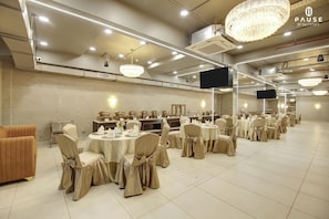 Un salón de banquetes con mesas redondas, sillas y una araña.