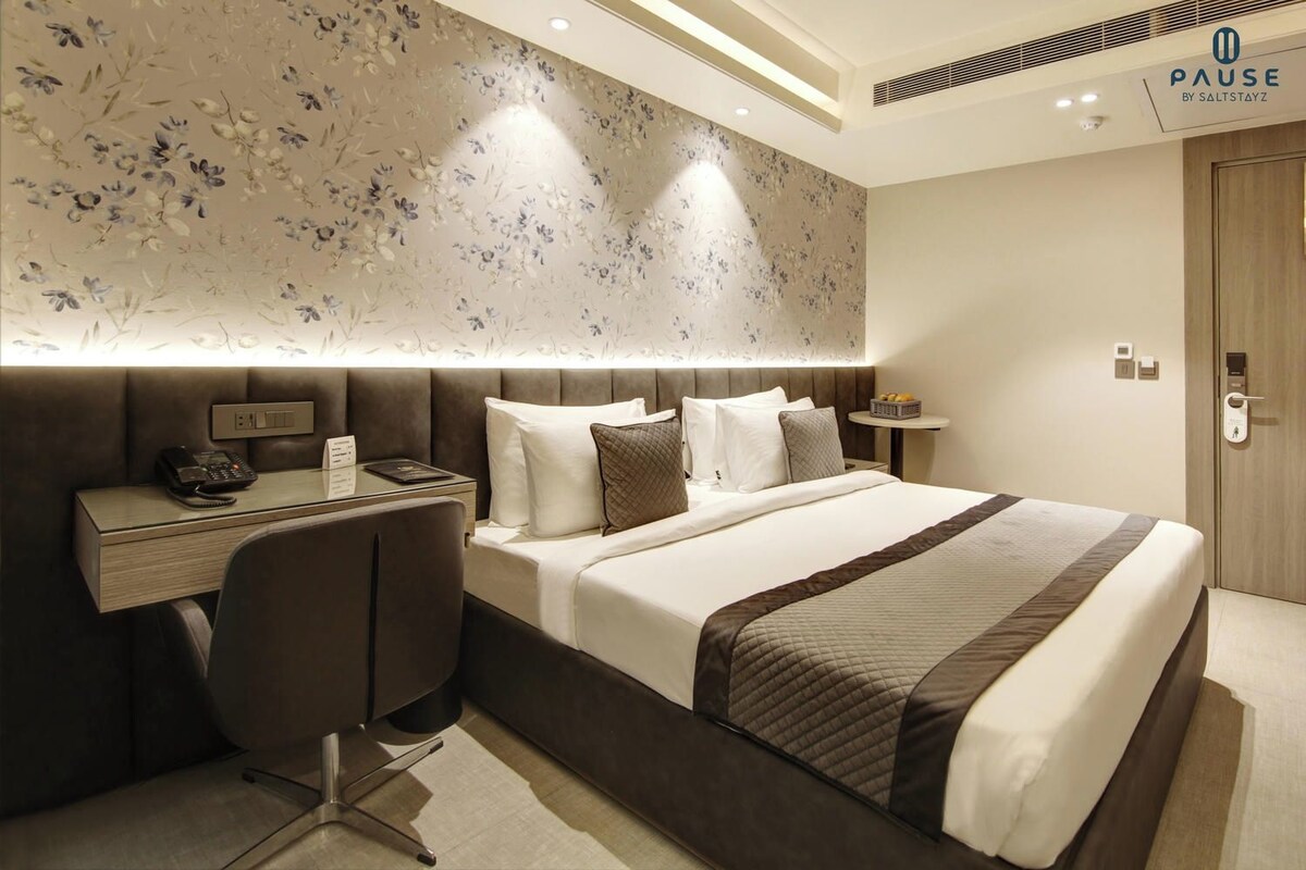 Ein modernes Hotelzimmer mit Bett, Nachttisch und Schreibtisch mit Telefon.