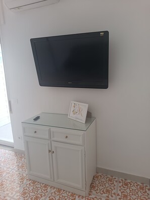 Ein Flachbildfernseher ist an einer Wand über einem weißen Schrank mit Schubladen angebracht.