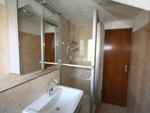 Ein Badezimmer mit Dusche, Waschbecken und Spiegel.