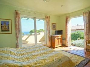 Ein Schlafzimmer mit einem Bett, einem Fernseher und Blick ins Freie.