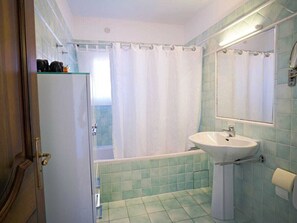Ein Badezimmer mit einem weißen Waschbecken, einer Duschvorhang und einem Spiegel.