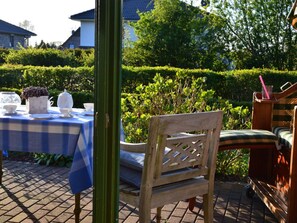 An outdoor seating area with a checkered tablecloth, a wooden chair, and a bench. - Holiday Apartment With 2 Bedrooms (Barkelsby)