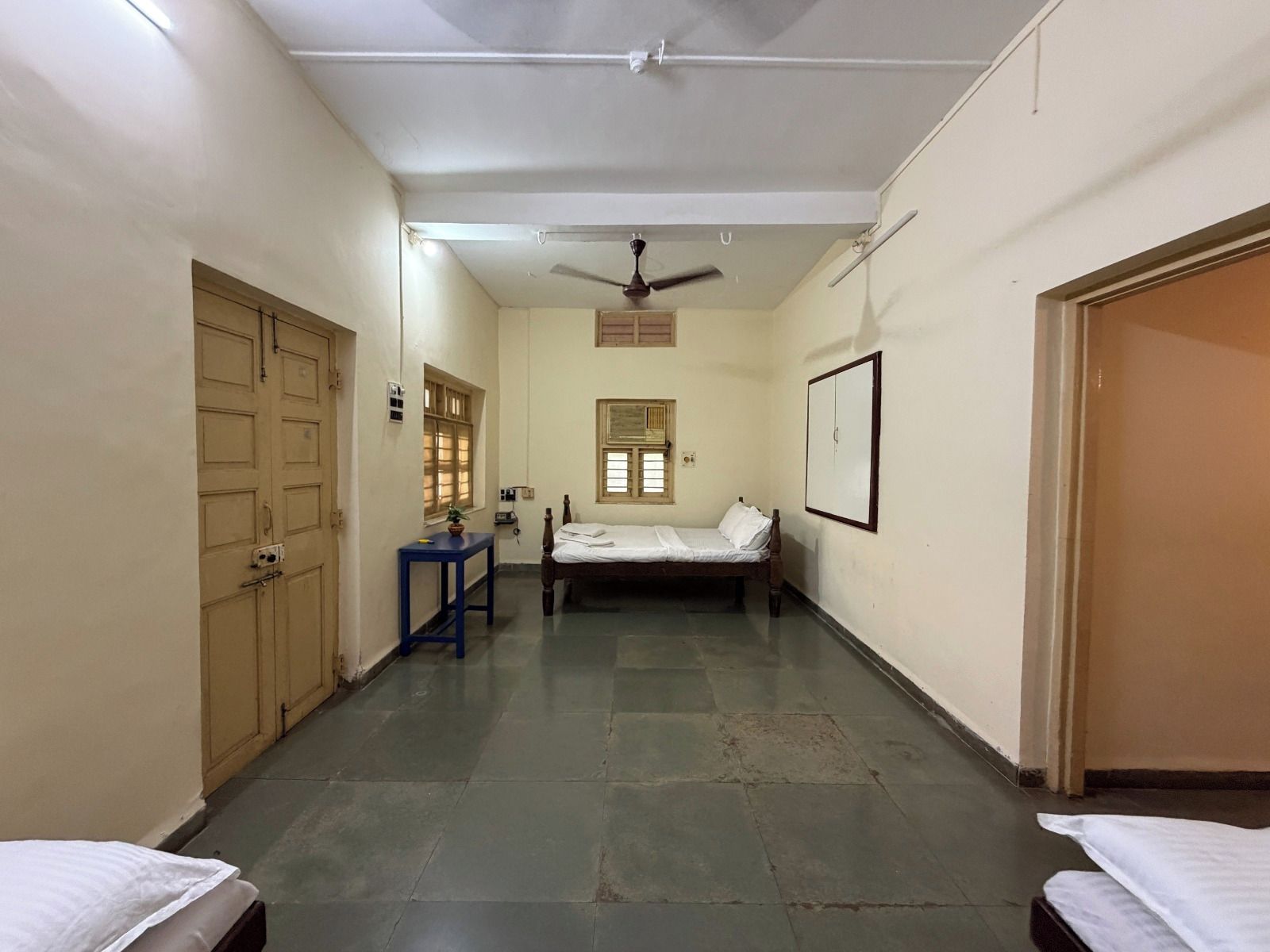A narrow corridor with a bed, a desk, and a wardrobe.