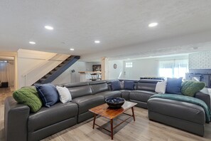 Una sala de estar moderna con un sofá modular, una mesa de centro de madera y una escalera que lleva a un nivel superior.