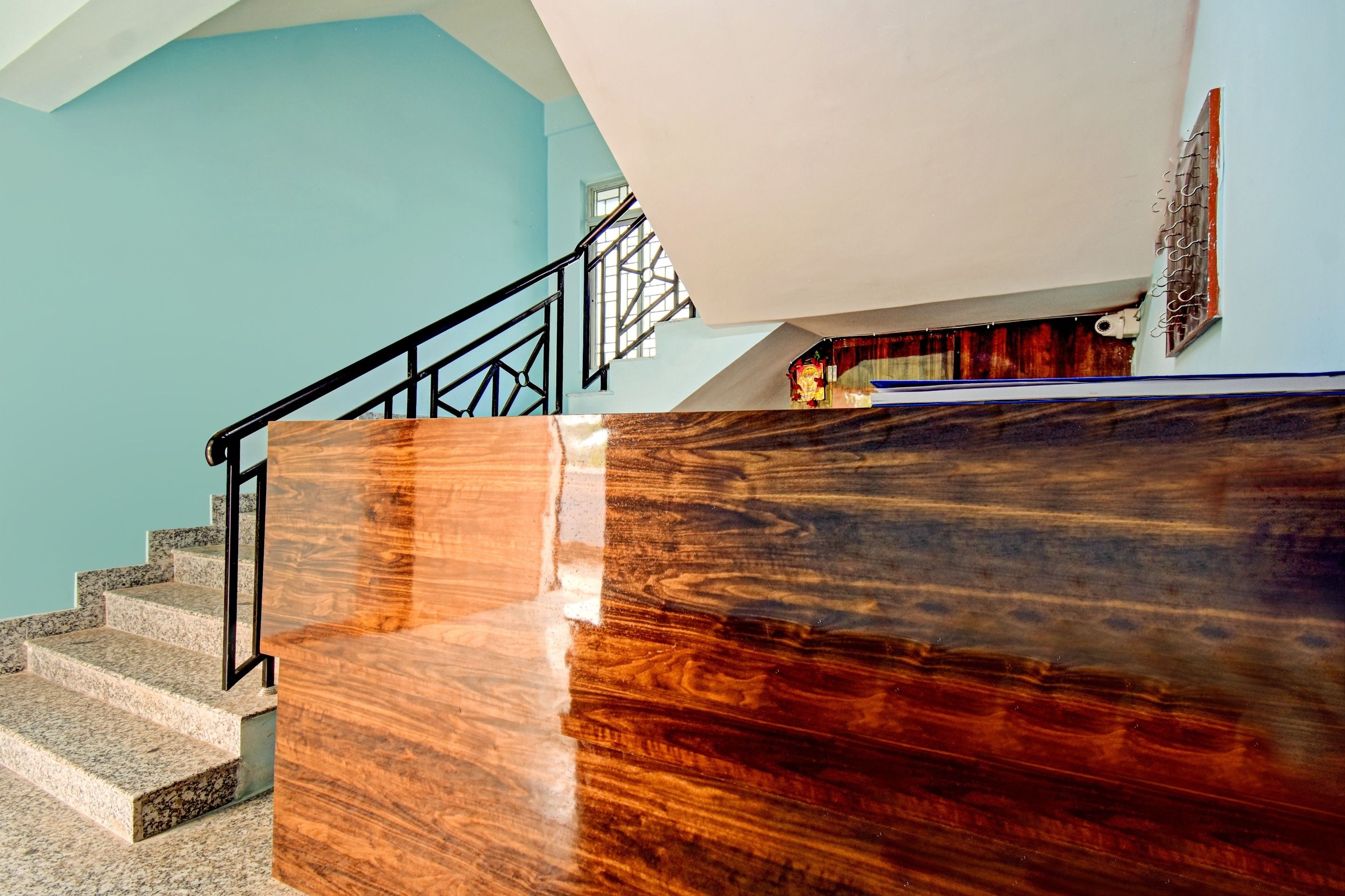 Una escalera con barandilla de madera y vistas a una habitación con pared azul y una ventana.