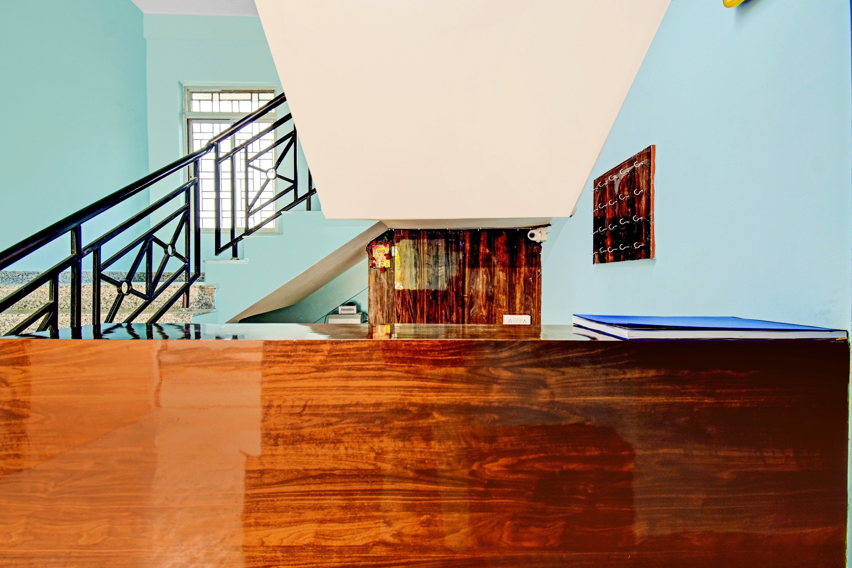A room with a wooden floor, a staircase, a window, and a wall with a framed picture.