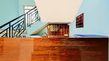 A room with a wooden floor, a staircase, a window, and a wall with a framed picture.