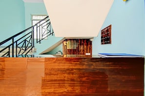 Ein Zimmer mit Holzboden, einer Treppe, einem Fenster und einer Wand mit einem gerahmten Bild.