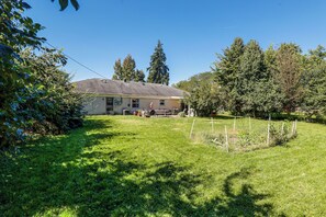 Une maison avec un jardin devant, une terrasse et une pelouse.