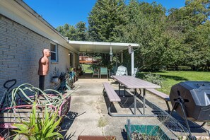 Ein Garten mit Grill, Picknicktisch und Sitzgelegenheiten im Freien.