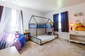 Ein Kinderzimmer mit Etagenbetten, einem Schreibtisch, einem Stuhl, einem Teddybären und einem Bücherregal.