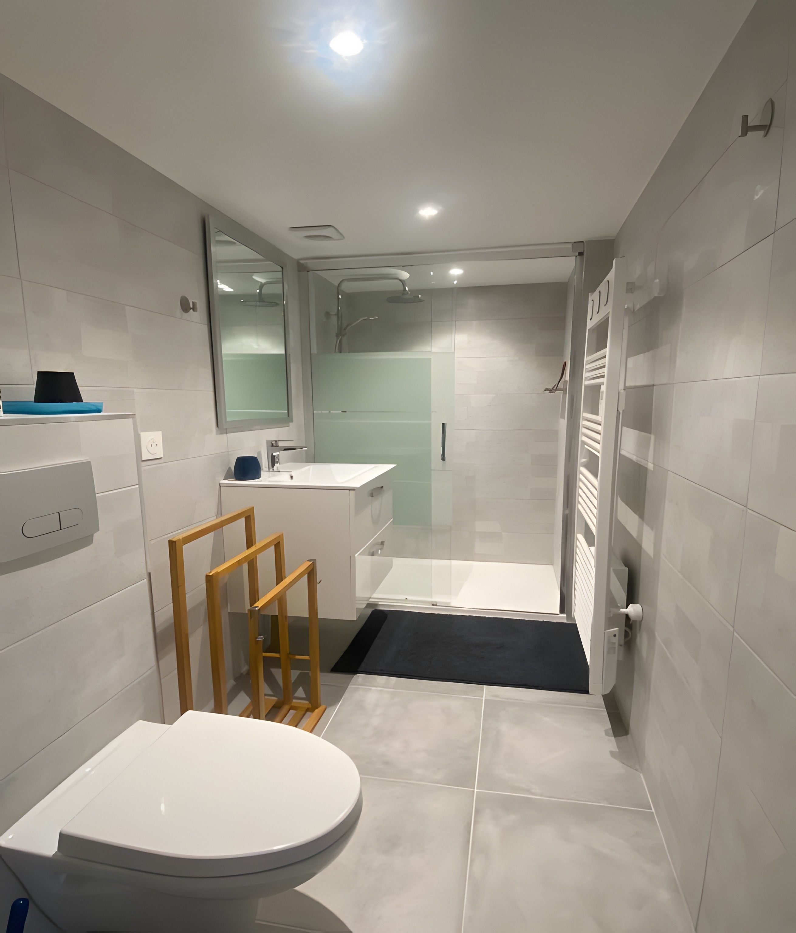 Une salle de bain moderne équipée de toilettes, d’un lavabo, d’un miroir et d’un espace douche.
