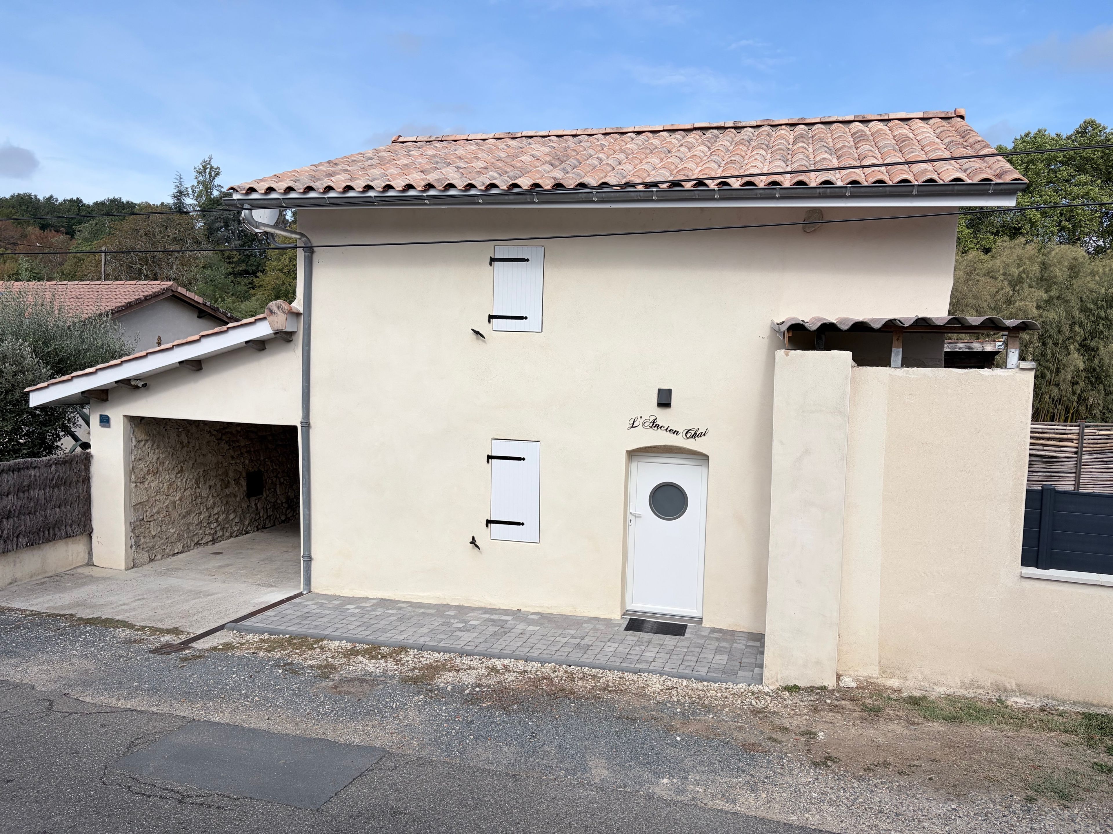 A two-story building with a tiled roof, a garage, and a small entrance door.