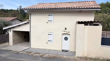A two-story building with a tiled roof, a garage, and a small entrance door.