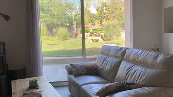 A modern living room with a sofa, a coffee table, and a view of a garden through a large window.