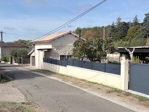 Una propietat residencial amb façana de pedra, teulat de teules i pati tancat per una tanca.