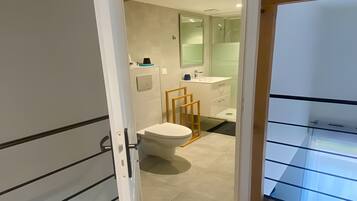 A modern bathroom with a toilet, sink, and shower.