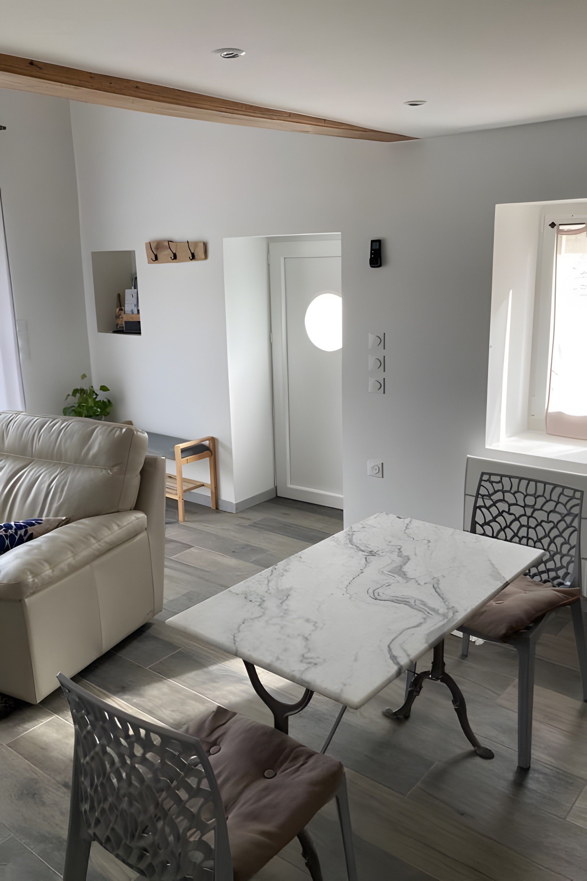 Ein modernes Wohnzimmer mit einem weißen Sofa, einem Marmortisch und einem gemusterten Sessel.