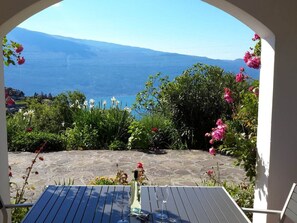 A table with a wine glass and bottle, overlooking a mountainous landscape with a clear view of the sea. - Casa Orio Apt. 2 (Tignale)