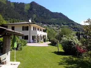 A two-story house with a garden and a view of a hillside. - Casa Orio Apt. 2 (Tignale)