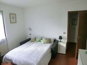 A bedroom with a bed, bedside tables, a lamp, and a door. - Casa Orio Apt. 2 (Tignale)