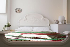 A bed with a white headboard, a colorful woven blanket, and a small potted plant on the nightstand. - Casa de Baixo in Coimbra (Coimbra)