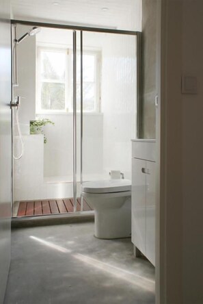 A modern bathroom with a shower, toilet, and a window providing natural light. - Casa de Baixo in Coimbra (Coimbra)