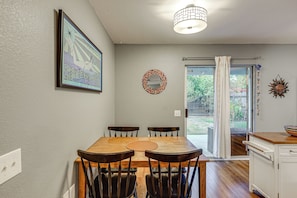 A dining area with a wooden table, four chairs, a ceiling light fixture, a framed artwork on the wall, and a decorative mirror. - Easy Airport Access! Austin Home w/ Patio (Austin)