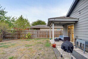 A backyard with a covered patio area, a wooden fence, and a grill cart. - Easy Airport Access! Austin Home w/ Patio (Austin)