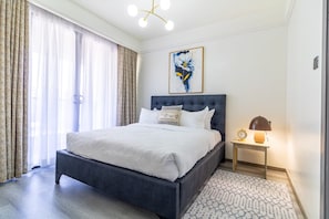 Une chambre à coucher moderne avec un grand lit, une table de chevet avec une lampe et un tableau au mur.