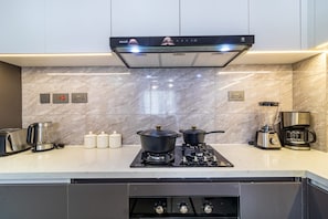 Une cuisine moderne équipée d’une cuisinière intégrée, d’une machine à café et d’un mixeur.