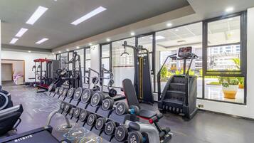 A gym with various exercise equipment, including dumbbells, a bench press, and cardio machines.