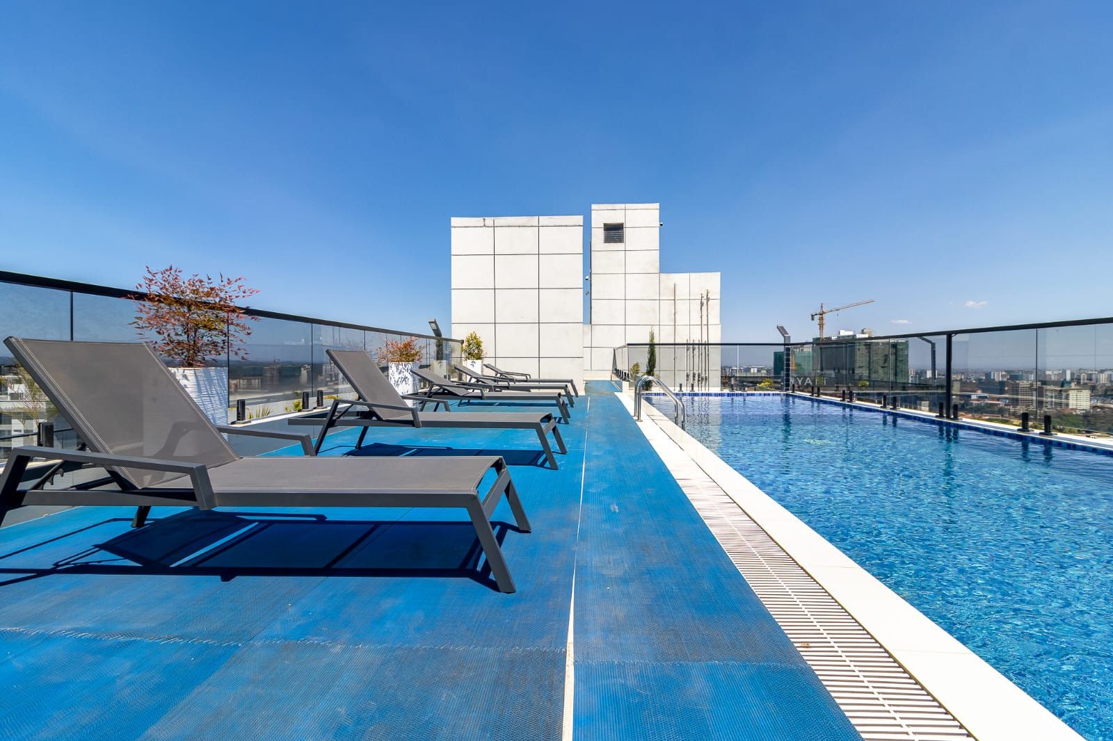 En pool på taket med solstolar och en fantastisk utsikt över stadens silhuett.
