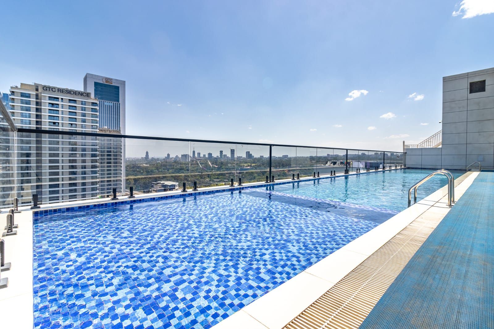 Une piscine sur le toit offrant une vue panoramique sur les gratte-ciel de la ville, entourée d’immeubles modernes.