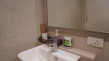 A bathroom with a white sink, a mirror, and toiletries on the countertop.