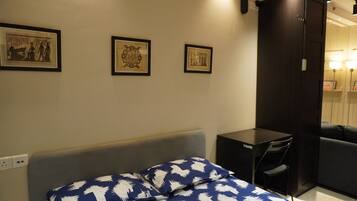 Ein Hotelzimmer mit Bett, Schreibtisch und Kleiderschrank. An der Wand hängen drei gerahmte Bilder.