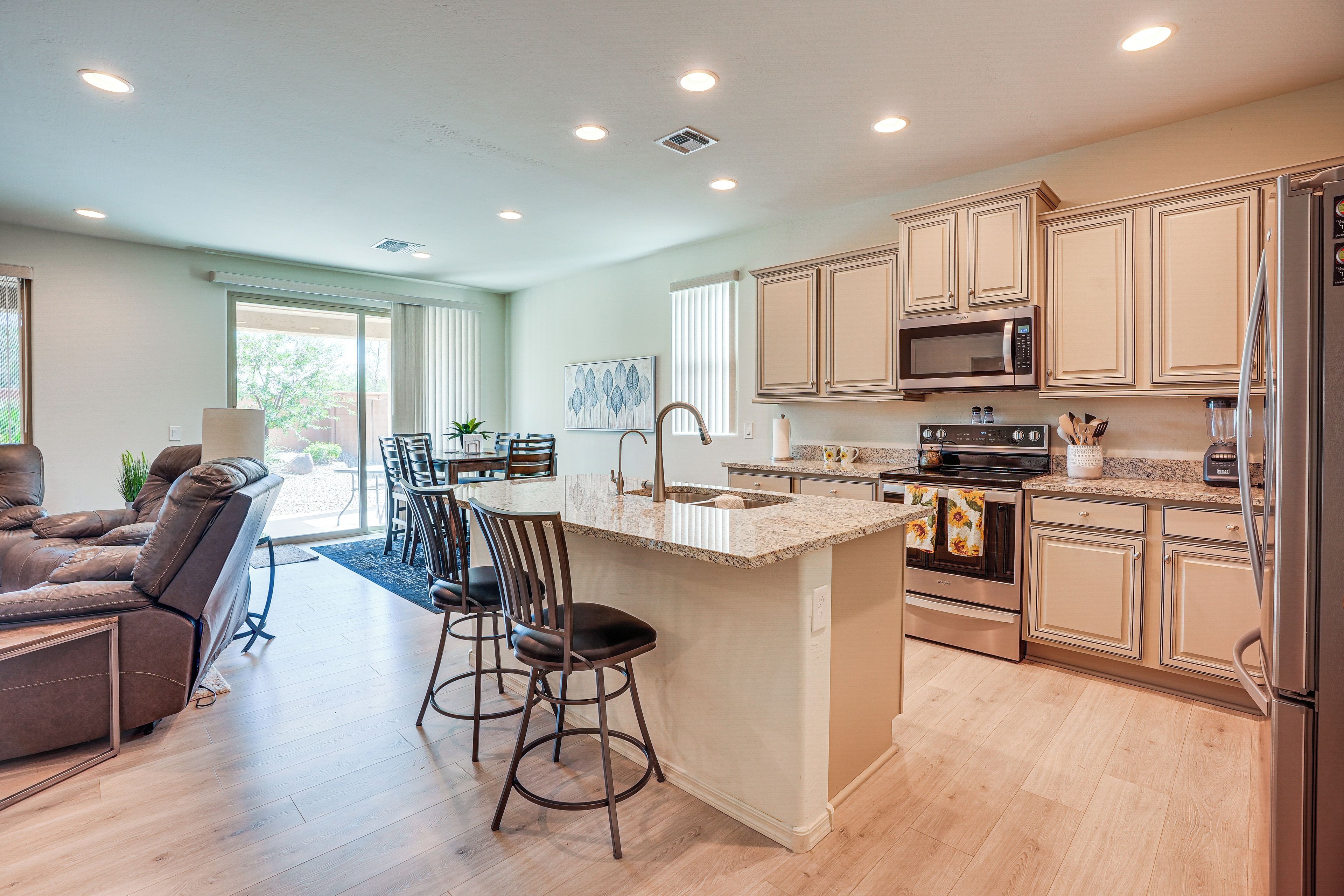 A modern kitchen with a central island, bar stools, and a dining area with chairs.