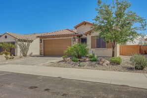 A residential house with a garage, a driveway, and a landscaped garden with cacti and shrubs. - Peaceful Home w/ Resort Perks in Buckeye (Buckeye)
