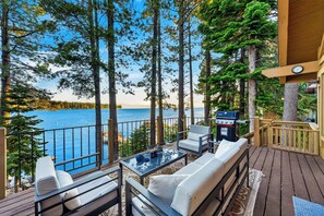 Una terraza con mobiliario exterior, una parrilla y vistas a un lago.