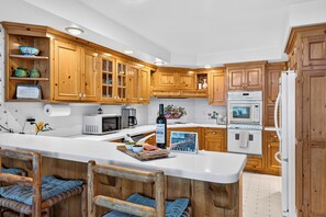 Eine moderne Küche mit Holzausstattung, einer zentralen Kochinsel inklusive Barhocker und integrierten Geräten.