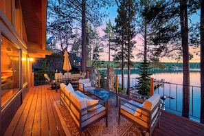 A deck with outdoor seating and a view of a lake surrounded by trees. - Lakefront Retreat • Boat Dock + Hot Tub | Near Beach | Meeks Bay Chalet (Tahoma)