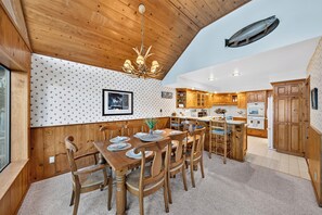 Interior em madeira com área de refeições, cozinha e um peixe grande no teto.