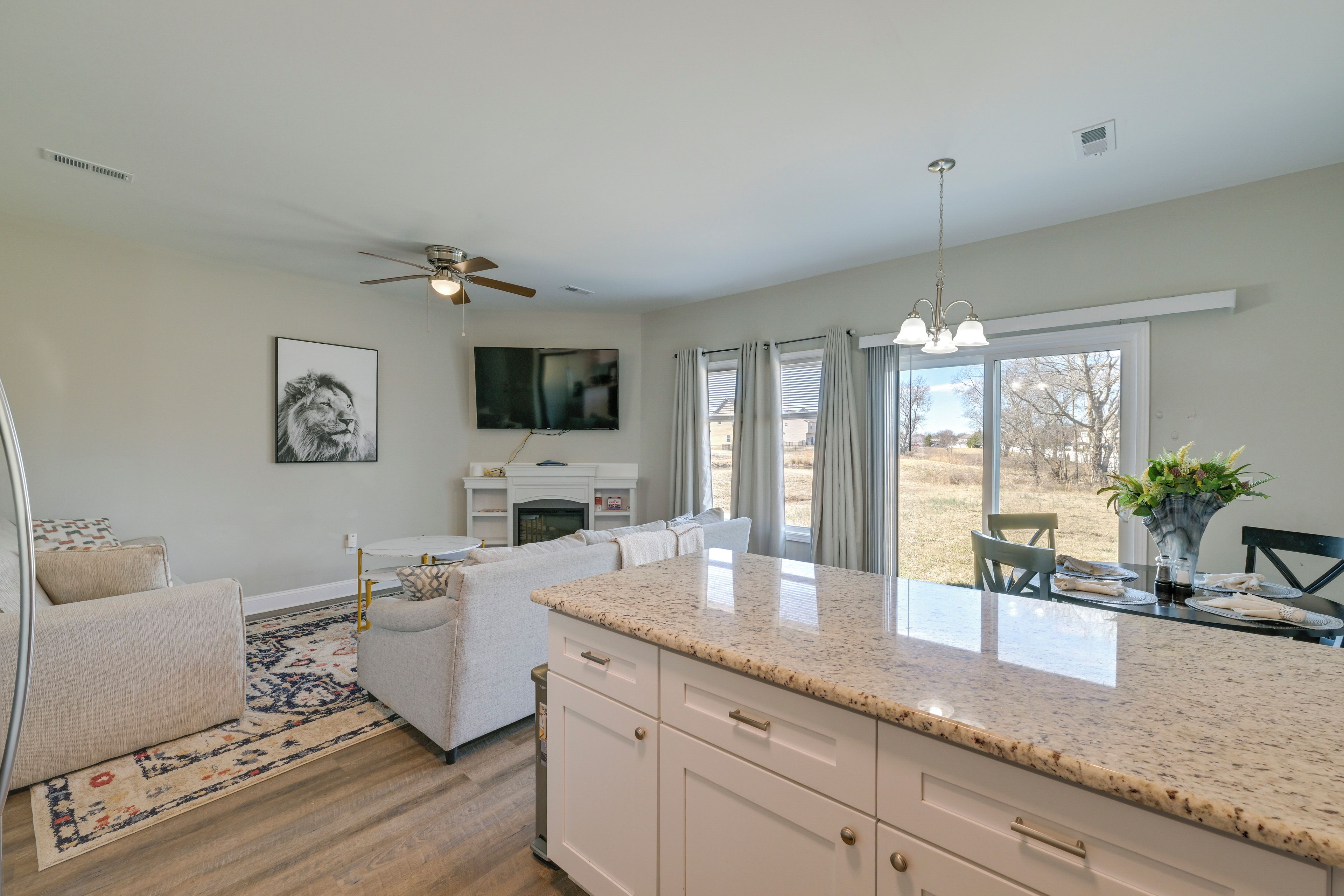 A modern kitchen with a granite countertop, white cabinetry, and a dining area with a table and chairs.
